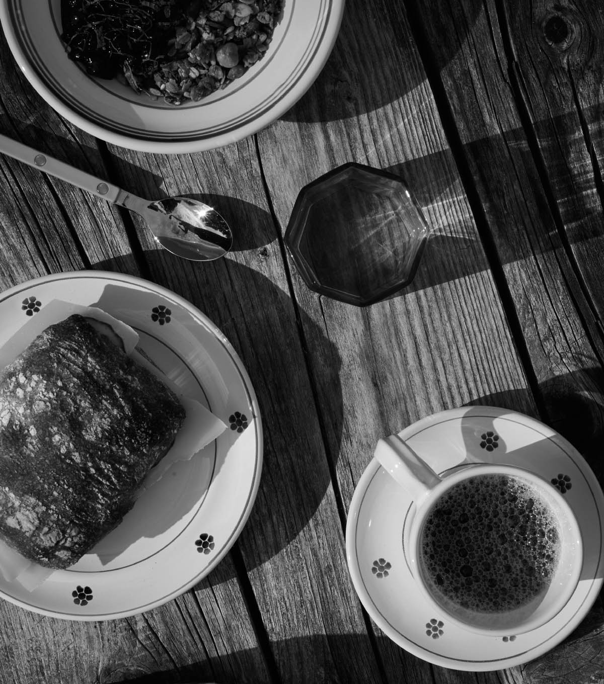 The breakfast table from above in morning sun — sourdough bread, coffee and granola