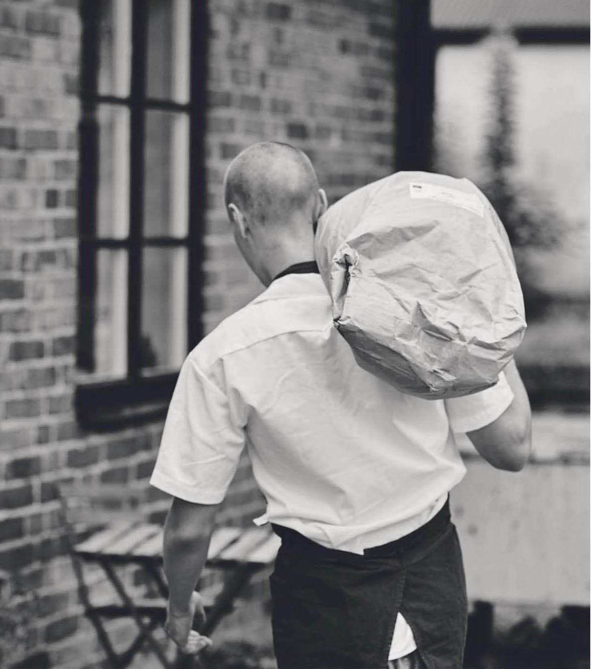 Man carrying a sack of flour along the brick façade